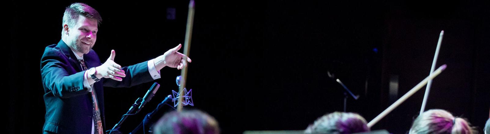 Conductor conducting with the bows of violins visible from below.